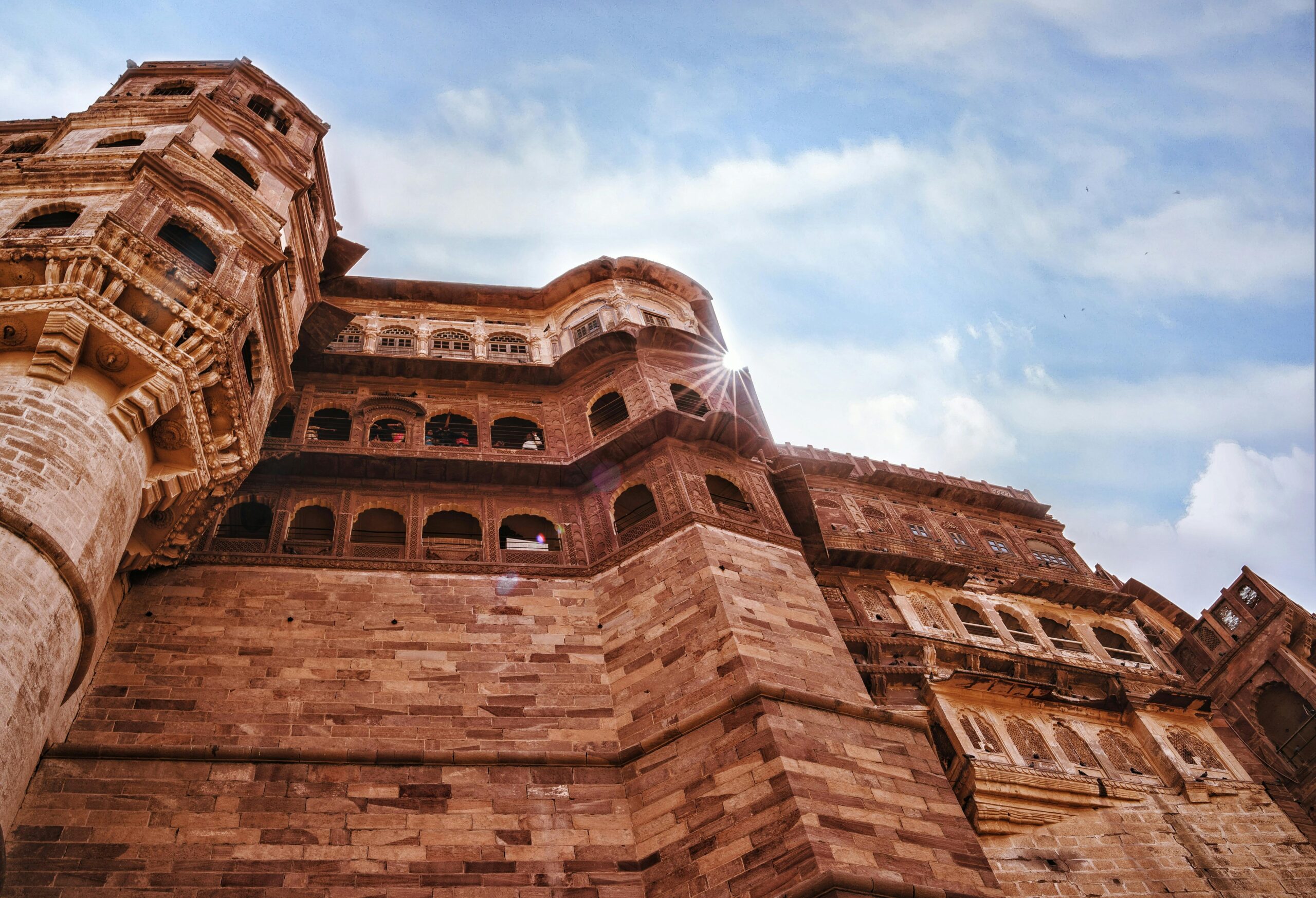 Low angle view of the historic Mehrangarh Fort with sunlit stone architecture.